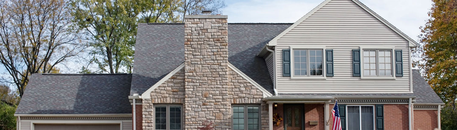 Newly built chimney cricket with fresh flashing behind a brick chimney in Plano, TX