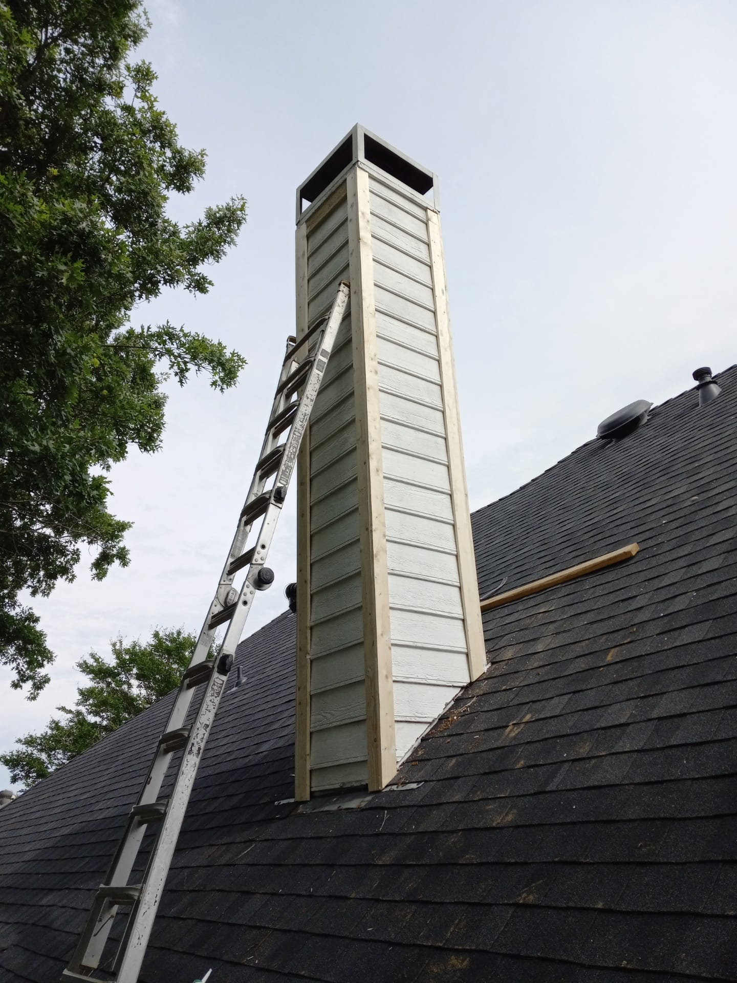 Chimney chase with new color-matched two-tone siding after replacement